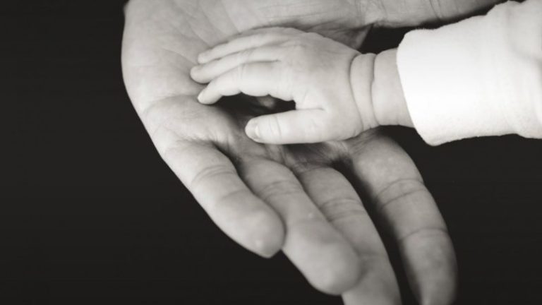Imagen de un bebé agarrando la mano de su madre
