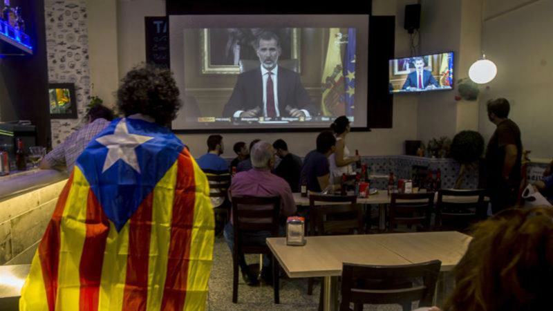 Un grupo de ciudadanos catalanes mira por la televisión el discurso del rey | EFE