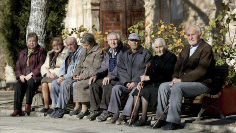 Un grupo de ancianos sentado en un banco de la localidad española de Olmeda de la Cuesta, una de las más envejecidas del país | EFE