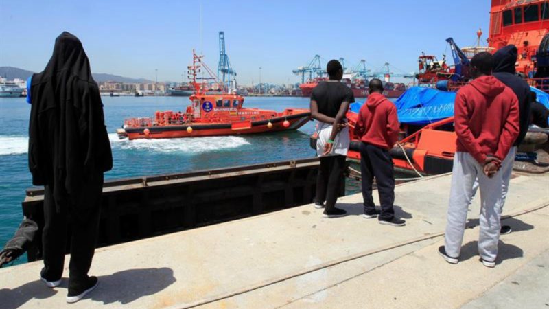 Varios inmigrantes rescatados días atrás, y que continúan en el puerto de Algeciras (Cádiz), observan la llegada de la embarcación de Salvamento Marítimo con los 19 inmigrantes rescatados hoy a bordo de dos embarcaciones en el estrecho de Gibraltar, lo que eleva a 96 el número de personas rescatadas hoy. EFE/A. Carrasco Ragel