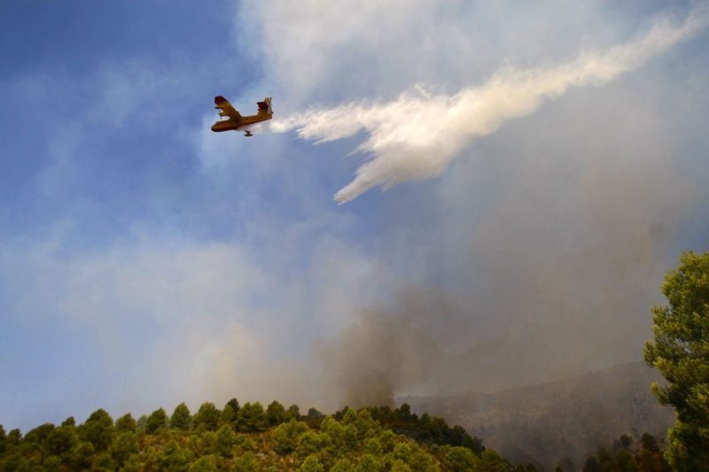 Un avión lanza agua sobre un incendio forestal.