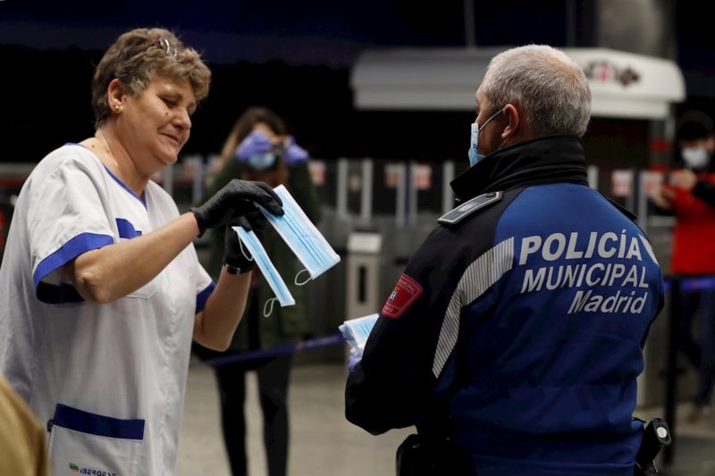 Policías entregan una mascarilla a una mujer en la estación de metro de Nuevos Ministerios en Madrid