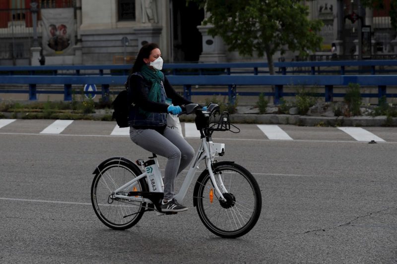Una mujer con mascarilla y guantes usa una bici de biciMad en Madrid