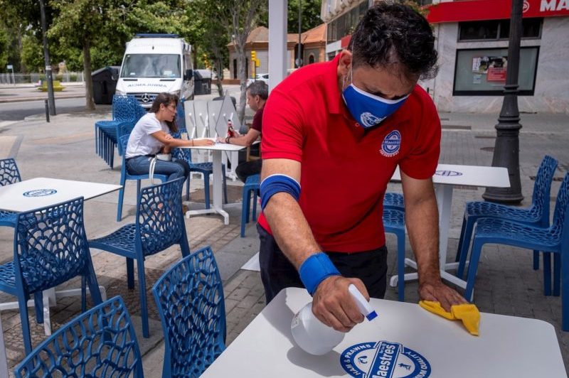 Un camarero limpia y desinfecta una mesa de de la terraza de un establecimiento