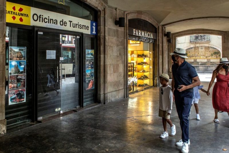 Una familia de visitantes ante una oficina de turismo cerrada en el centro de Barcelona.
