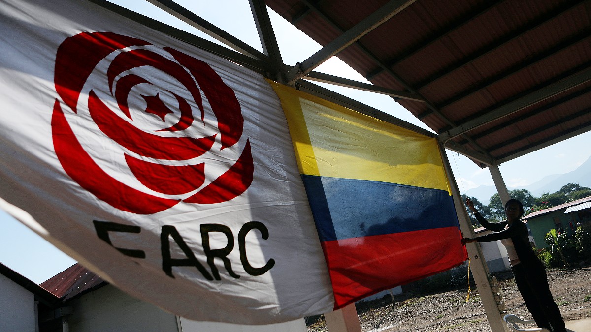 Una mujer cuelga una bandera colombiana junto a la bandera del partido FARC en un campo de reintegración en Pondores, Colombia 1 de agosto de 2019 - Reuters
