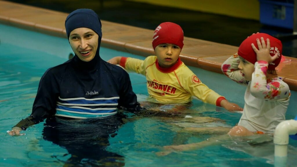 Una mujer musulmana viste un burkini en una piscina junto a sus hijas. Reuters