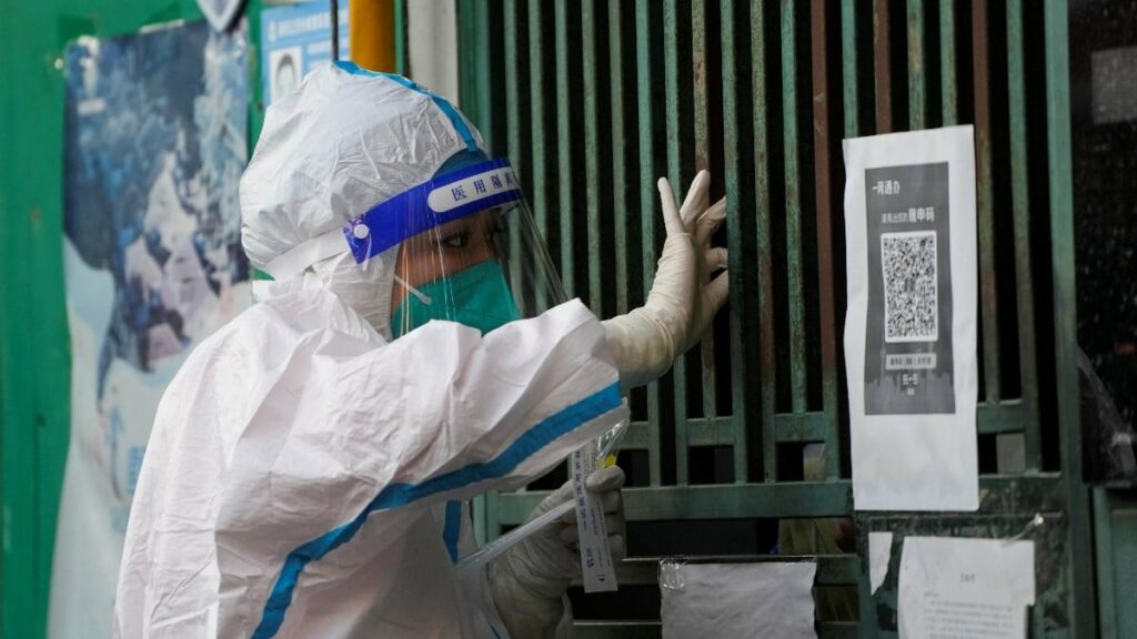 Una sanitaria realiza un test covid a una persona a través de la reja de una puerta en Shanghai. Reuters