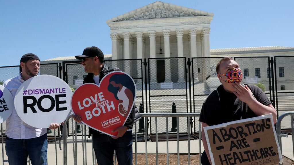 Dos manifestantes sostienen carteles provida junto a un manifestante proaborto frente a la Corte Suprema de EE.UU. Reuters