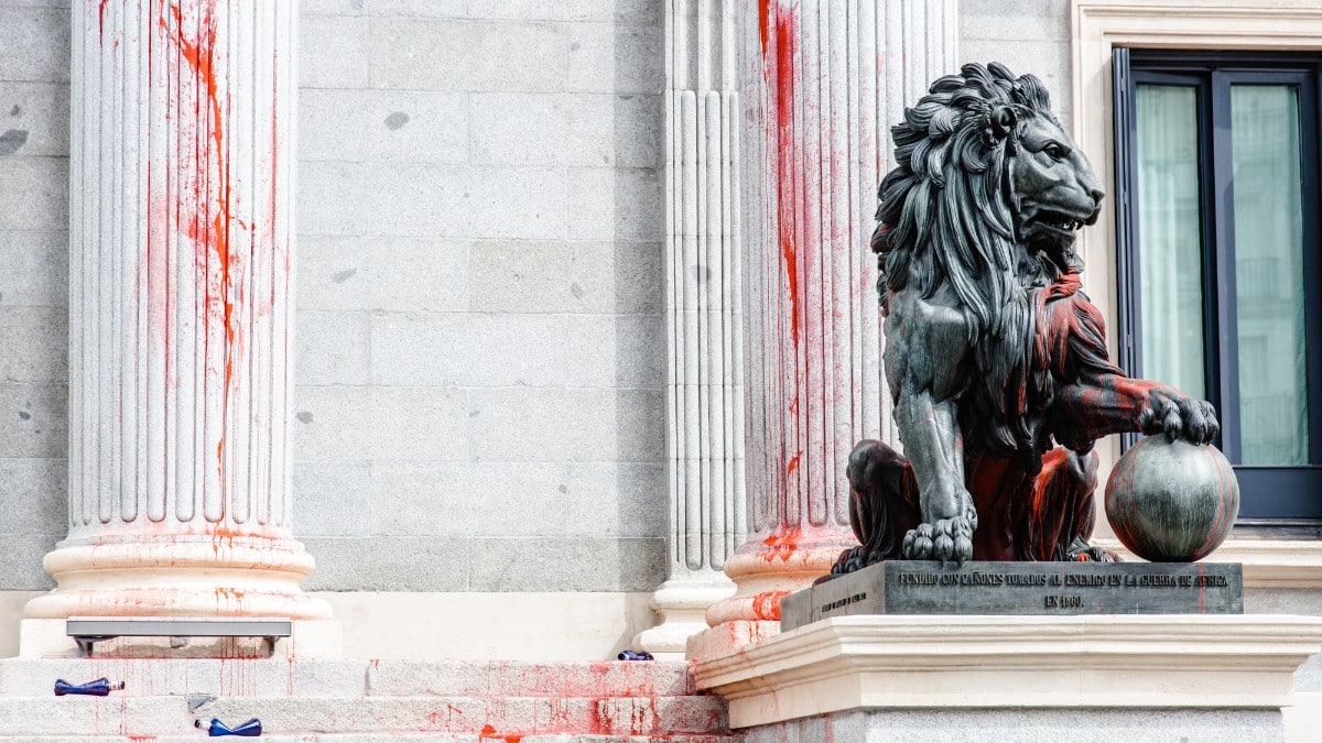 Uno de los leones del Congreso de los Diputados y las columnas teñidas con pintura roja por activistas. Europa Press