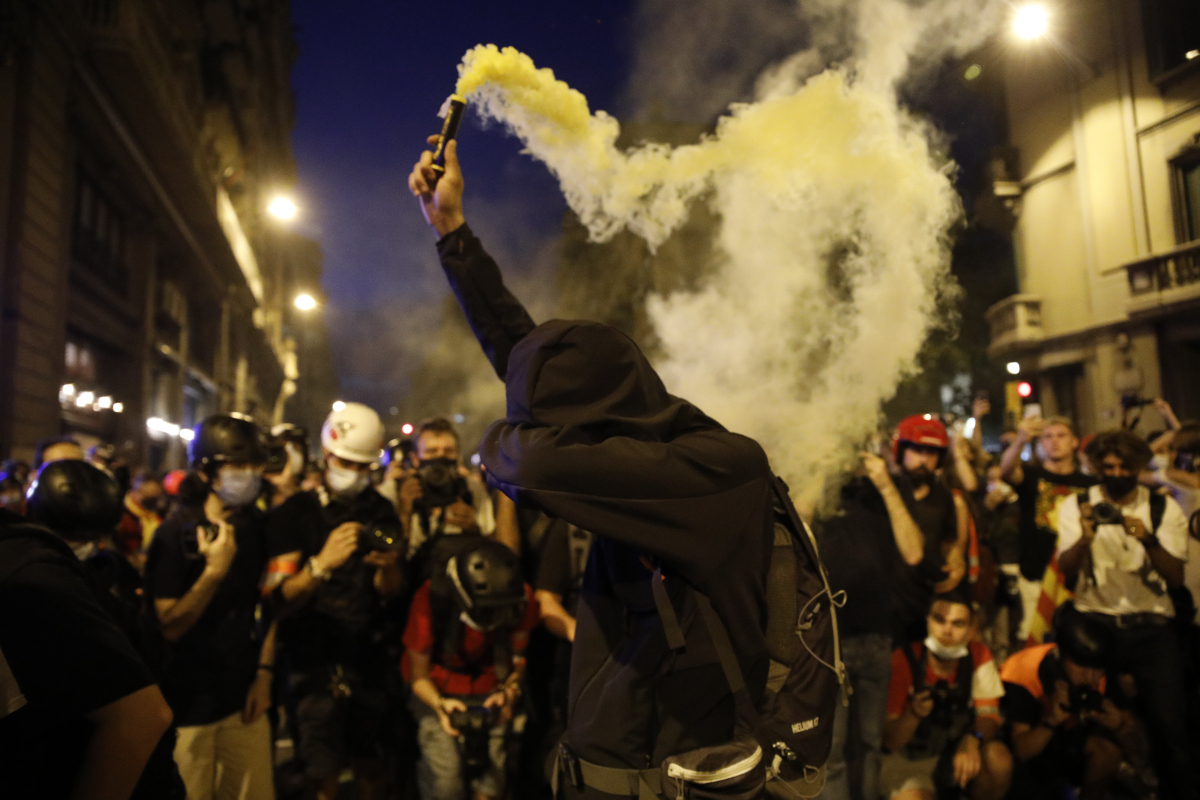 Cinco encapuchados queman una bandera española antes de empezar la manifestación por la Diada en Barcelona